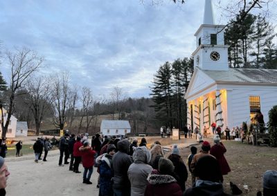 Group of tourists in winter clothes gathering outside the The Center Meetinghouse at Old Sturbridge Village, Sturbridge, MA.