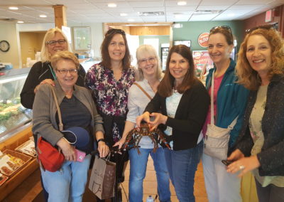 Tourists holding a lobster for their meals at Blount Clam Shack - an experience included in the Life by the Bay Tour.