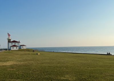 View of the Watch Hill Lighthouse with the flagpole on the side.