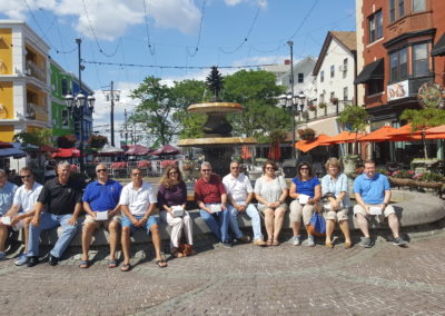 Tourists sitting around the fountain at DePasquale Square - an experience included in The Italian Experience Tour.